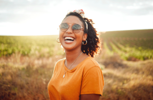 a woman wearing sunglasses while standing in a field smiles knowing that she completed her prescription drug addiction program
