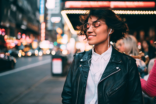 woman outside in a city with headphones on listening to music