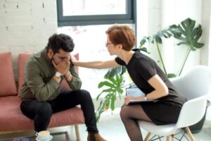 a distraught man sits in a therapist's office while she consoles him and suggests to him an individual therapy program in frederick