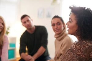 three people listen to a woman speaking to a group of people during motivational interviewing therapy in frederick